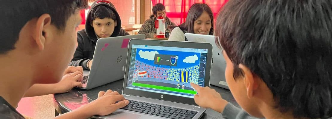 Dos niños viendo el monitor de una netbook con un videojuego que diseñaron
